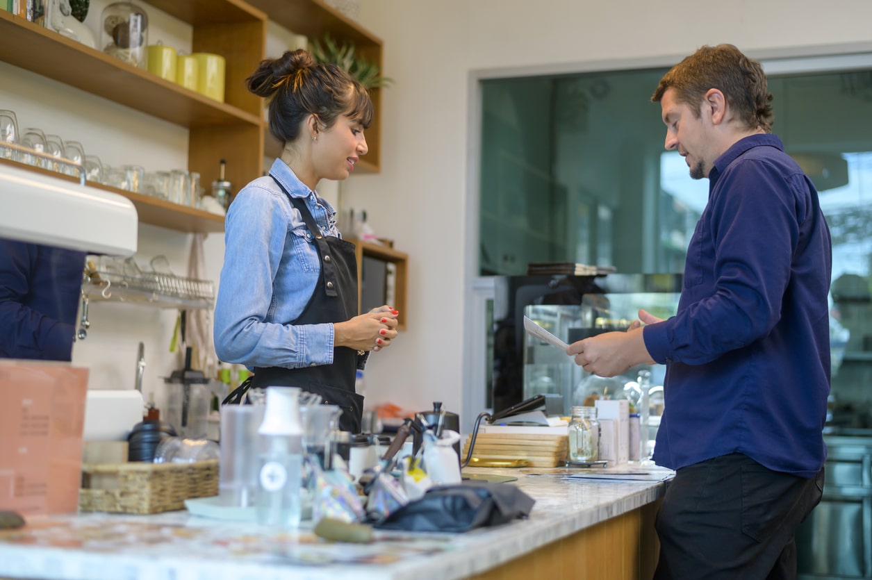 Young service minded barista woman with customer in coffee shop
